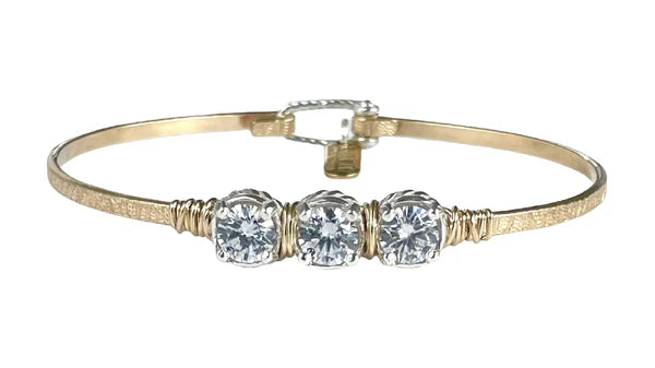 Gold bracelet with three clear gemstones on a white background
