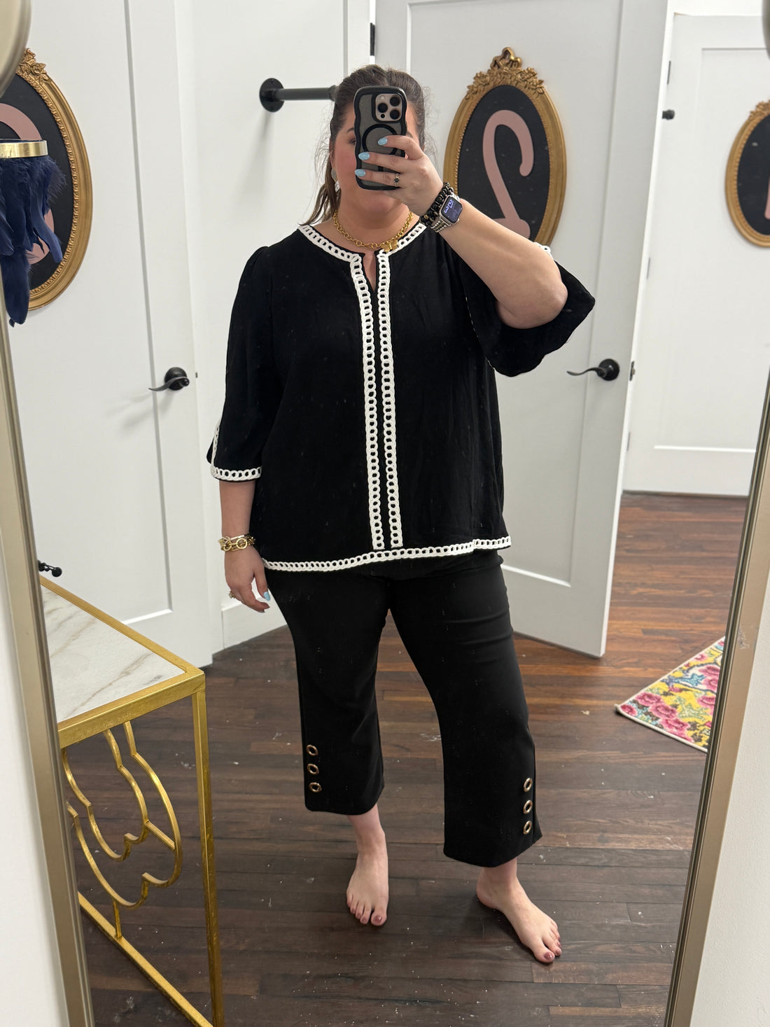 Person wearing a black outfit with white trim in front of a mirror.