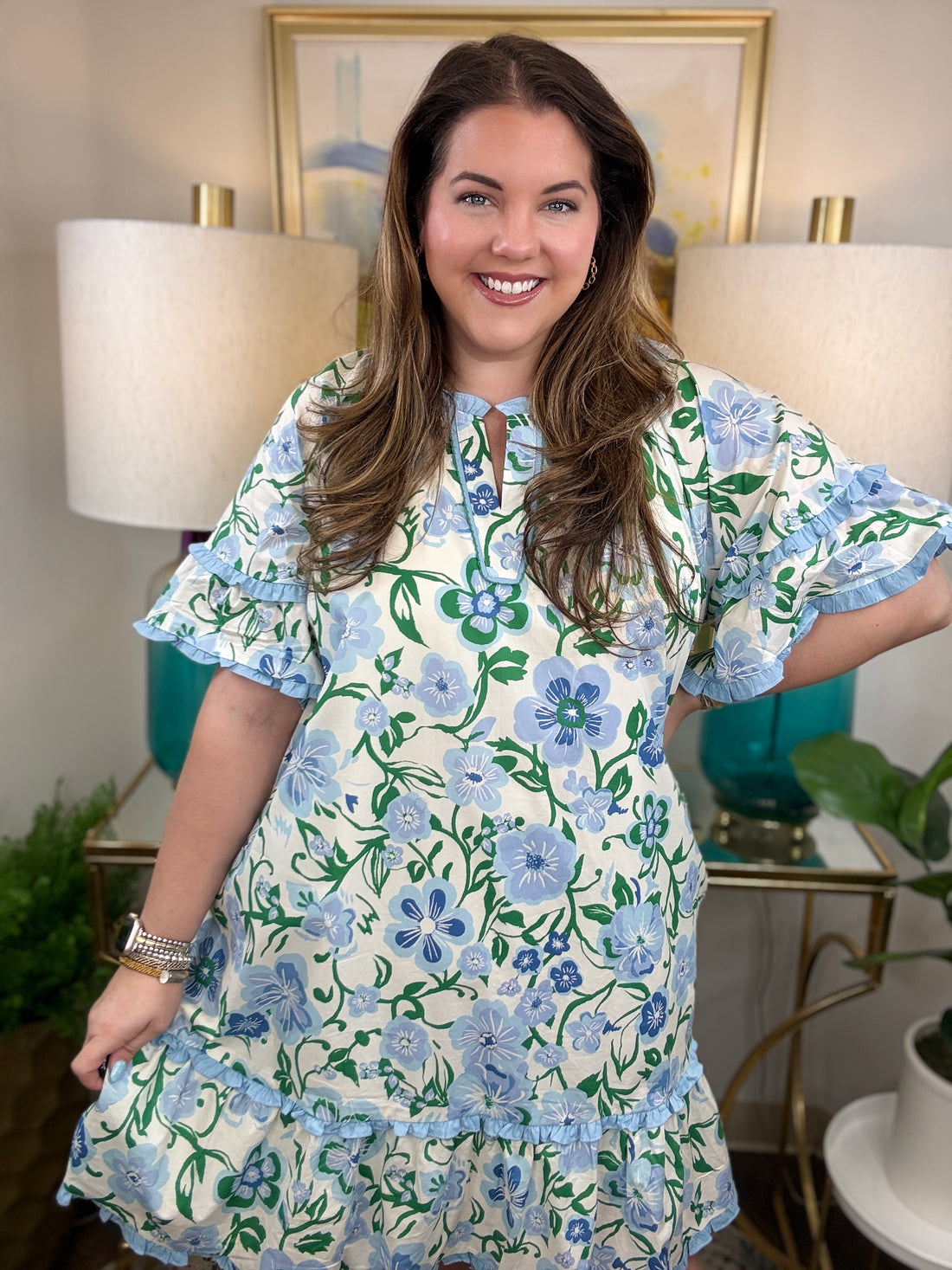 Woman wearing a blue and white ruffled dress with greenery accents.
