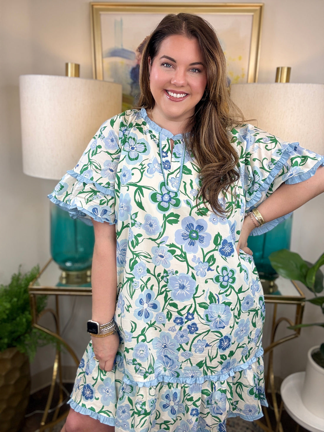 Woman wearing a blue and white ruffled dress with greenery accents.
