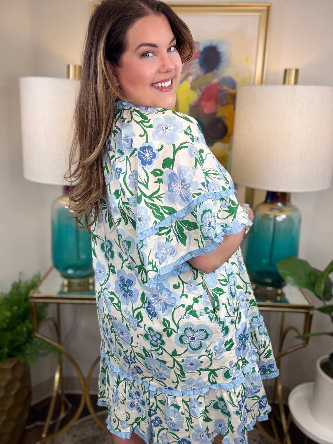 Woman wearing a blue and white ruffled dress with greenery accents.