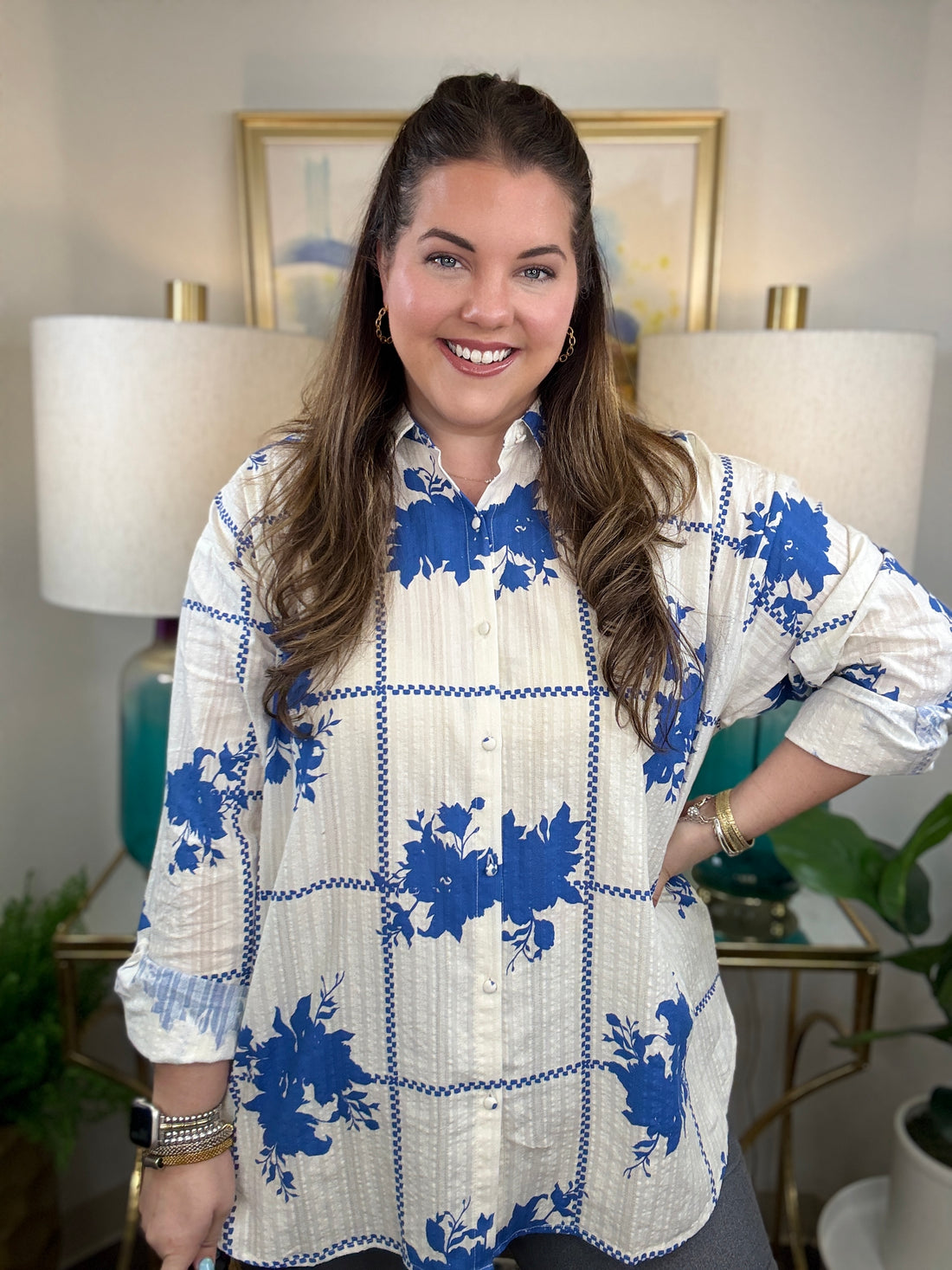 Woman wearing a white button down blouse with royal blue floral accents.