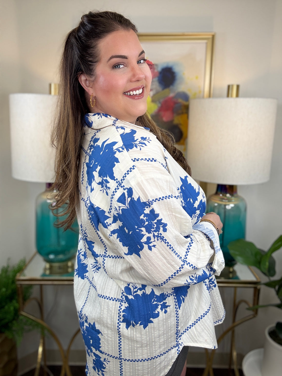 Woman wearing a white button down blouse with royal blue floral accents.