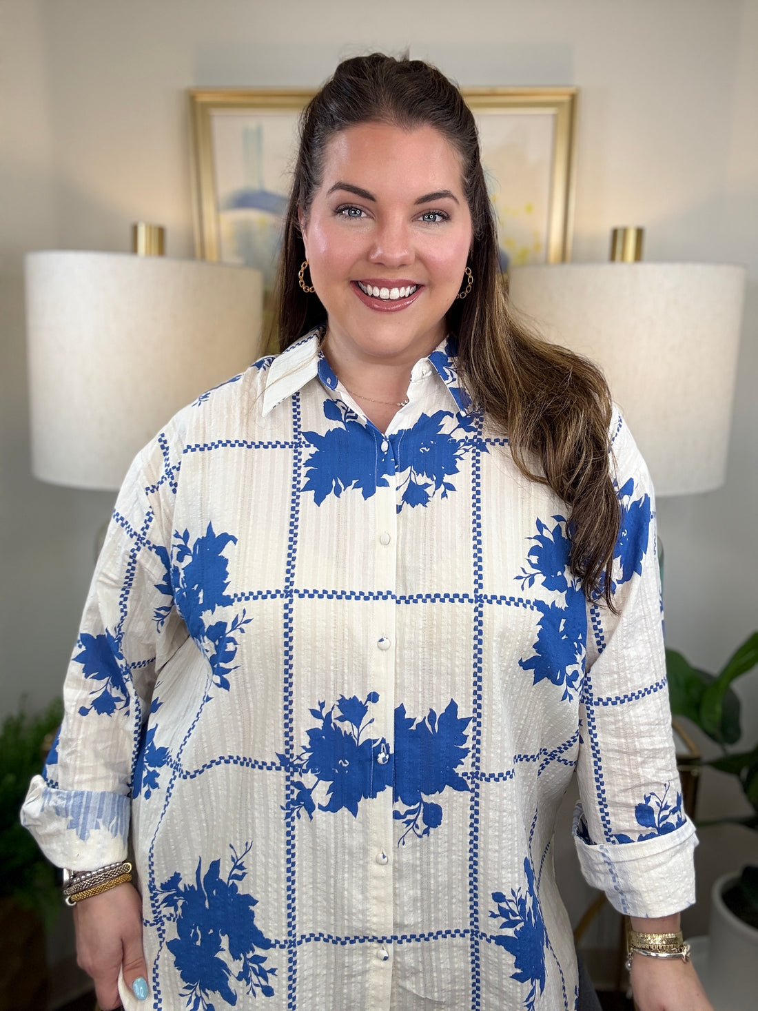 Woman wearing a white button down blouse with royal blue floral accents.