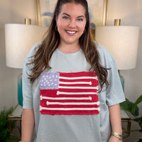 Woman wearing a dusty blue american flag shirt.