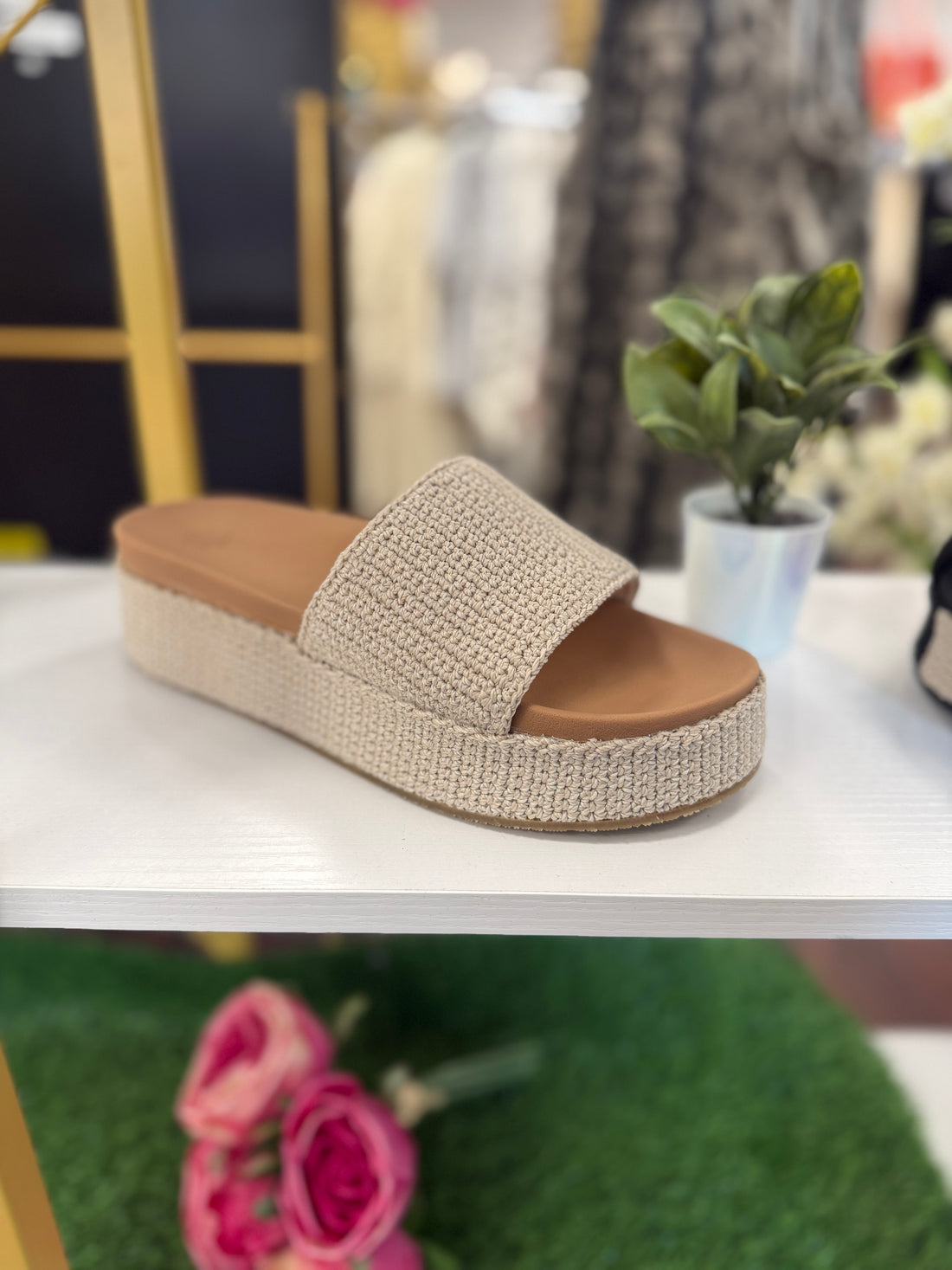 Beige sandal with brown sole on a white surface, blurred background