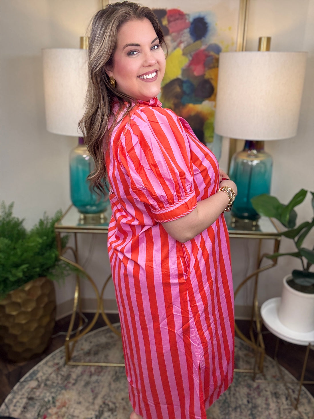 Woman wearing a red and pink striped maxi dress. 