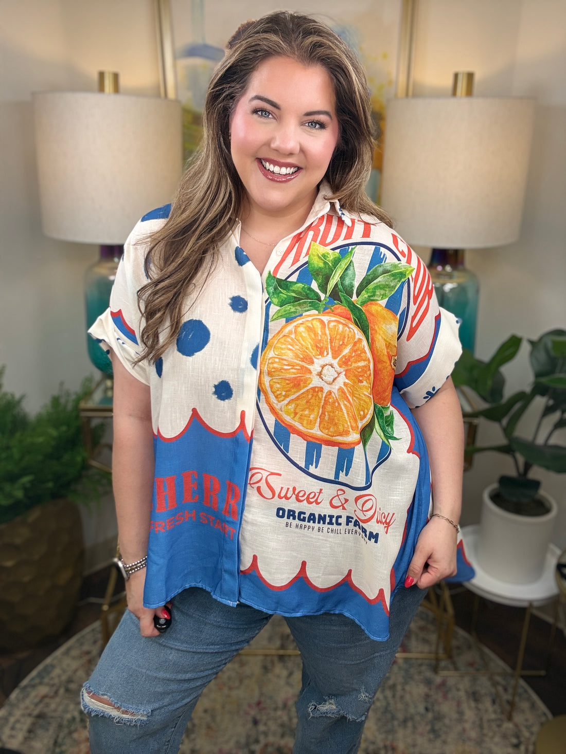 Woman wearing a bright colorful linen blend with a fruit pattern button down top. 