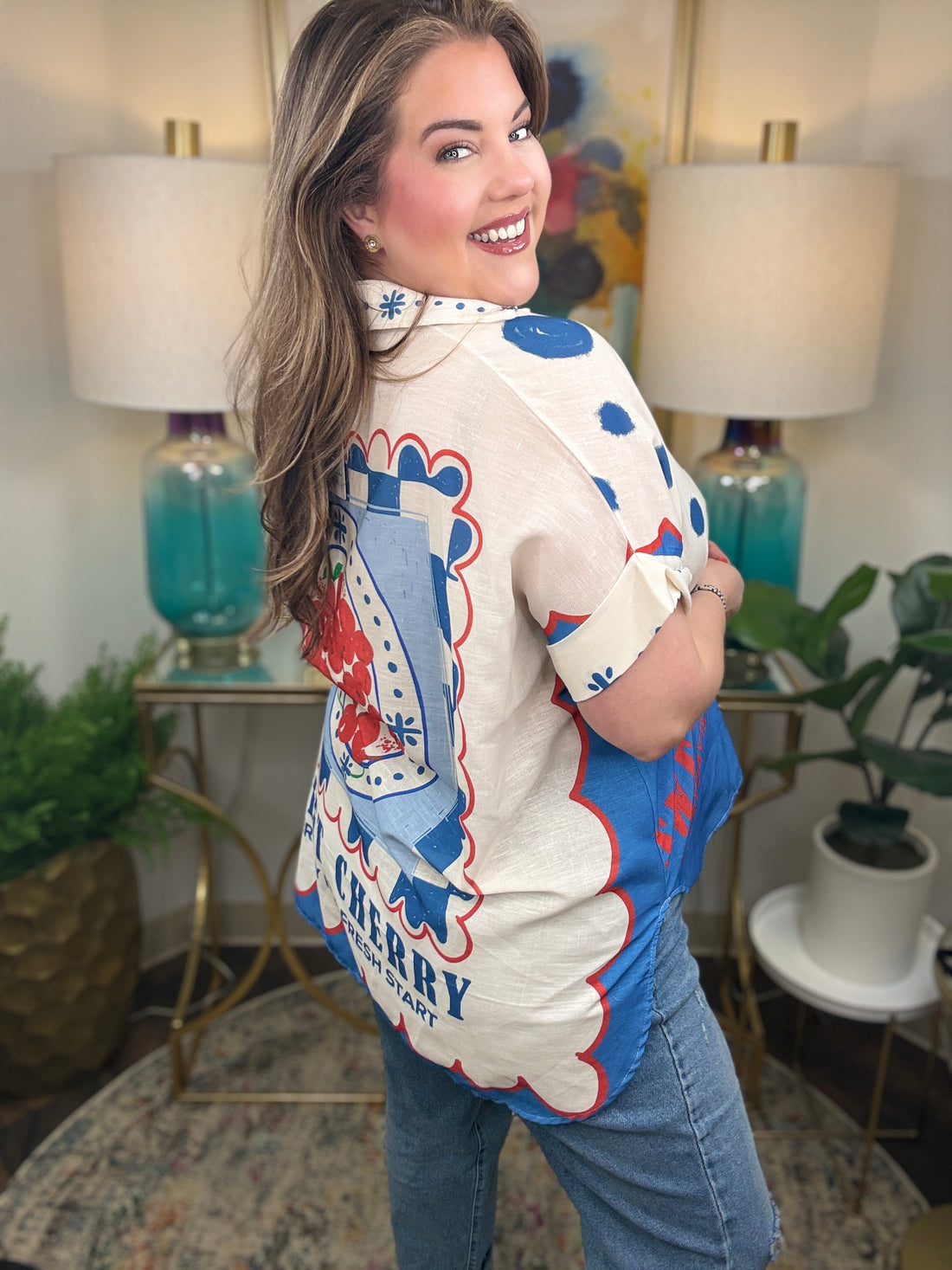 Woman wearing a bright colorful linen blend with a fruit pattern button down top. 