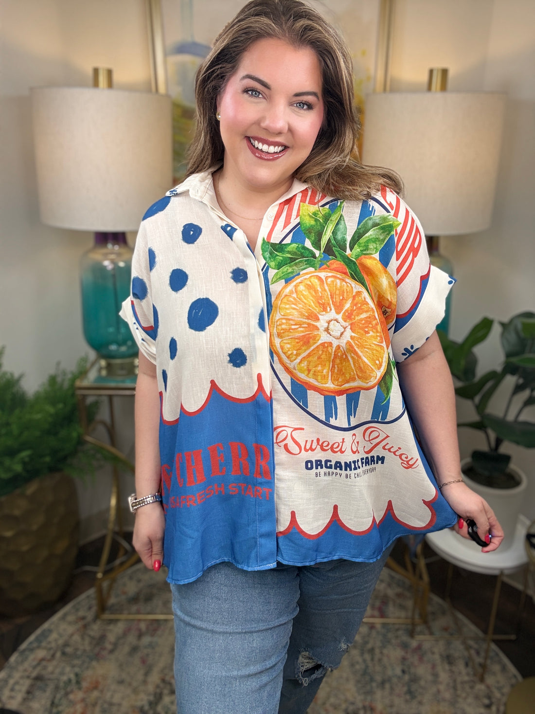 Woman wearing a bright colorful linen blend with a fruit pattern button down top. 