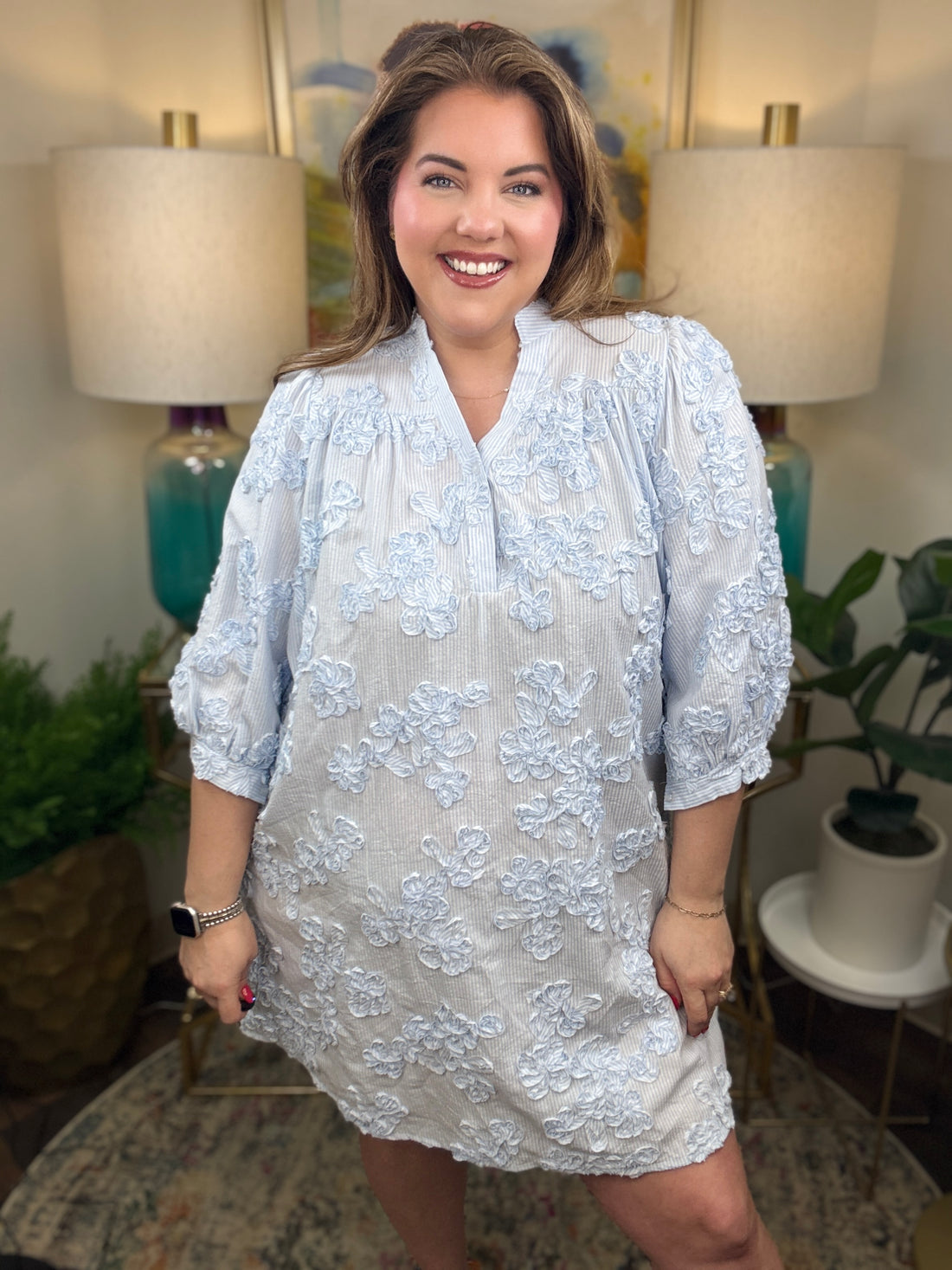 Woman wearing a blue and white seer sucker dress with floral appliques all over
