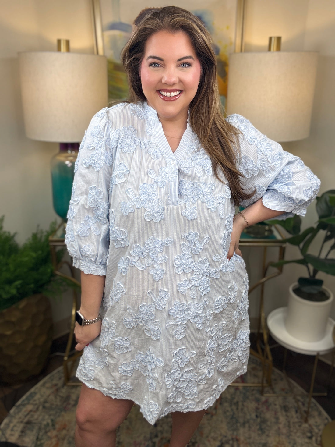 Woman wearing a blue and white seer sucker dress with floral appliques all over