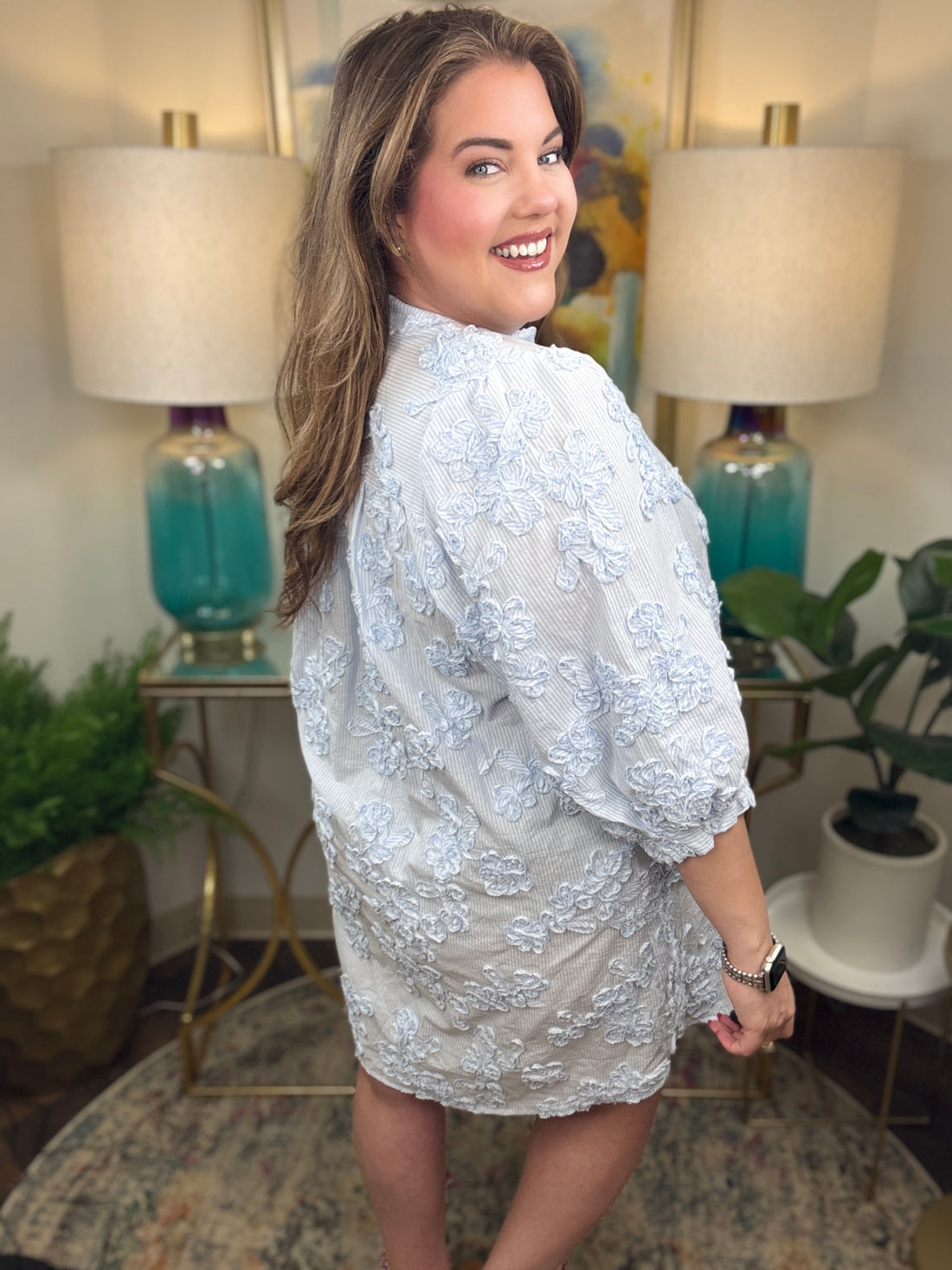 Woman wearing a blue and white seer sucker dress with floral appliques all over