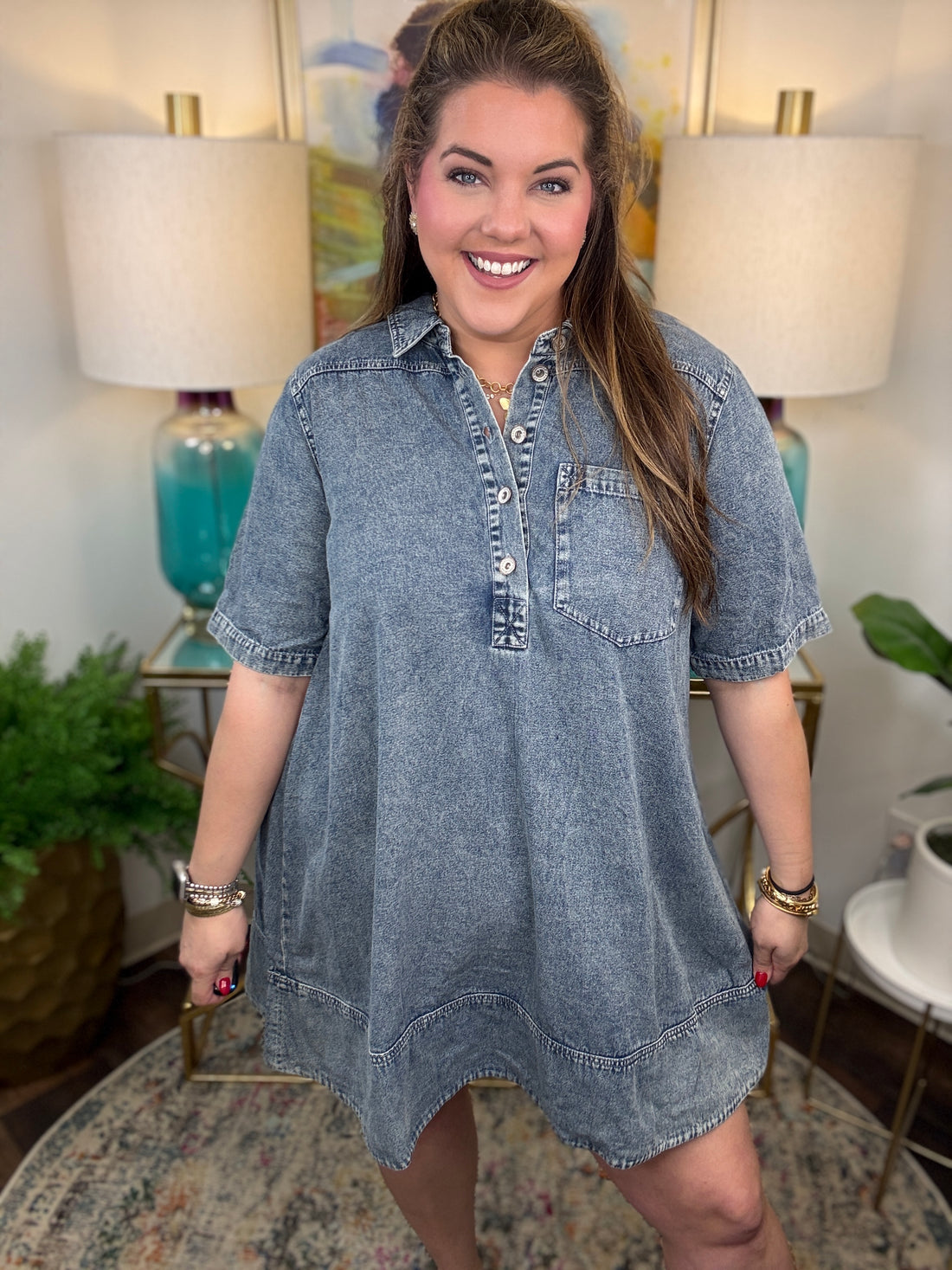 Woman wearing a denim dress in a room with lamps and decor.