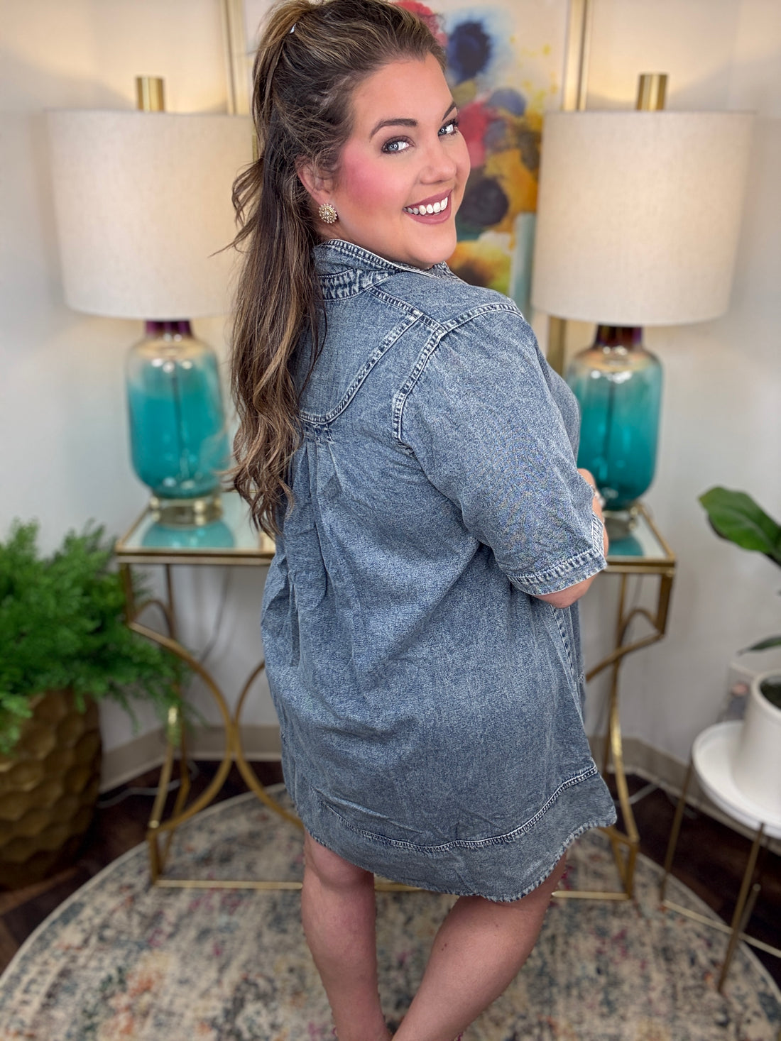 Woman wearing a denim dress in a room with lamps and decor