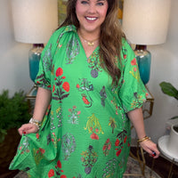 Woman wearing a green floral dress in a home setting with lamps and decor.