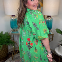 Woman wearing a green floral dress in a home setting with lamps and decor.