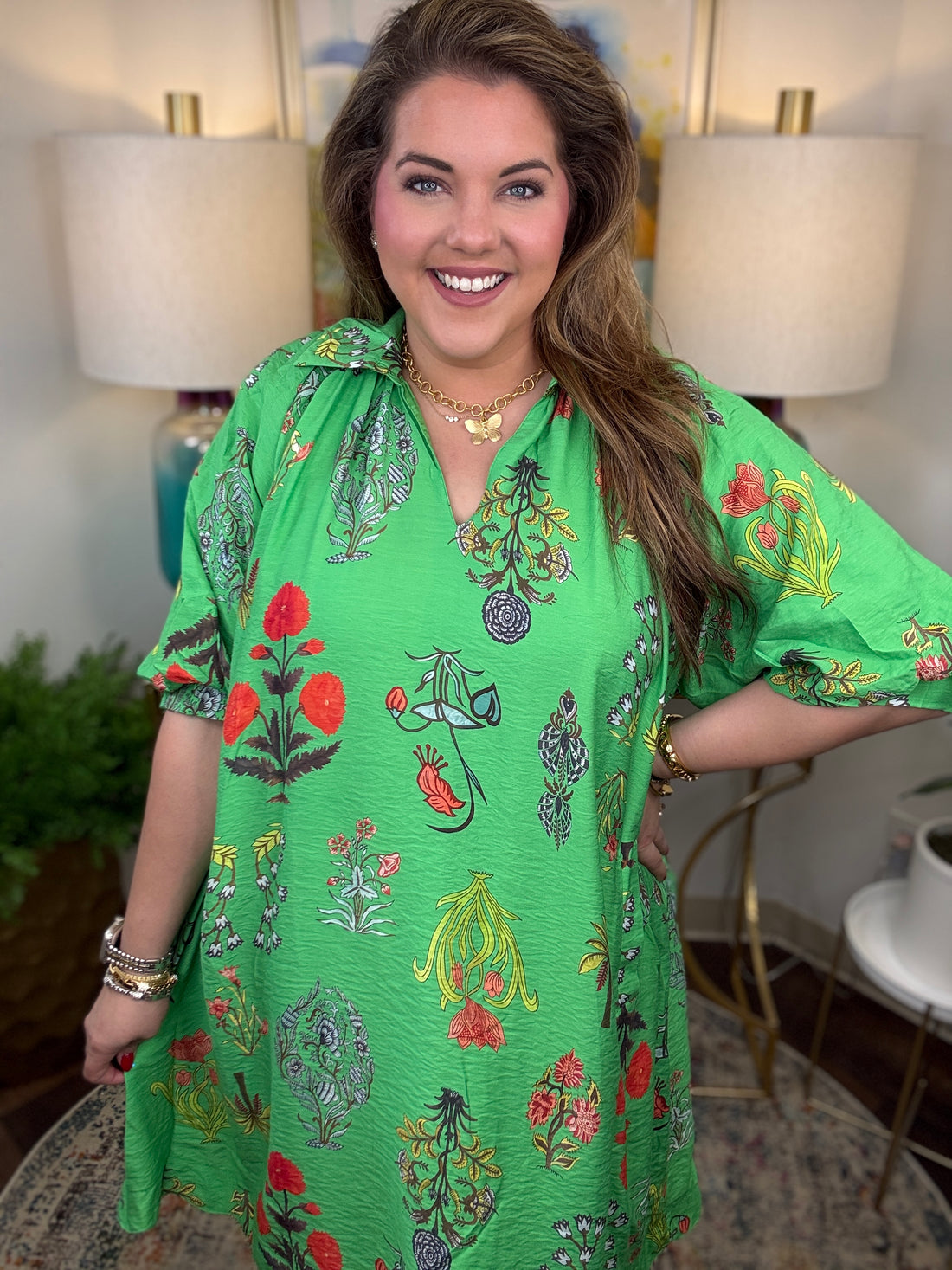 Woman wearing a green floral dress in an indoor setting with lamps and decor.