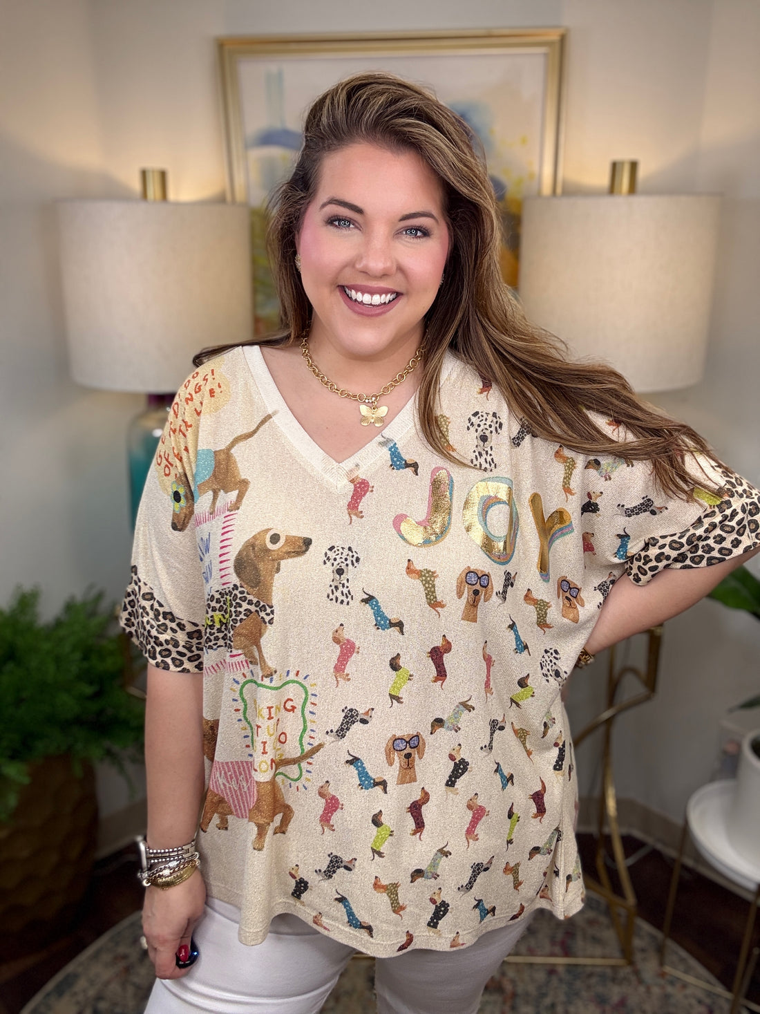 Woman wearing a patterned blouse with animal designs in a room with lamps and a painting.