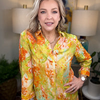 Woman wearing a colorful floral blouse in an indoor setting with lamps and plants.