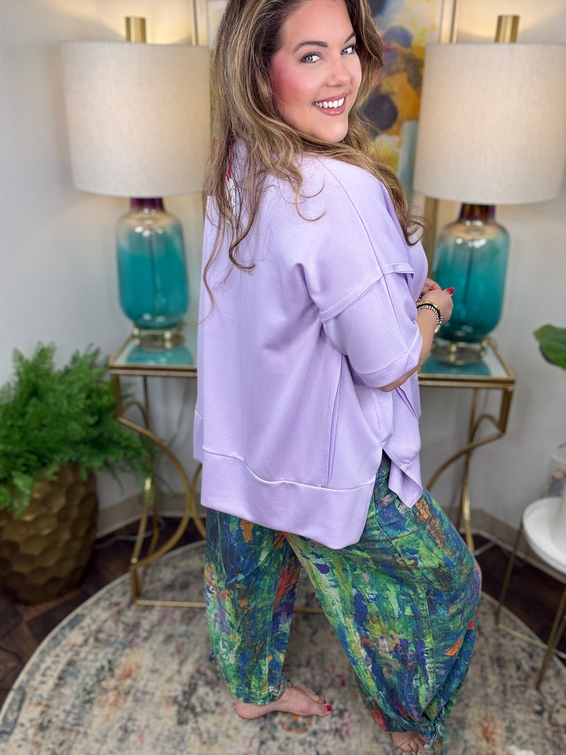 Woman wearing colorful denim pants with vibrant brush stroke pattern. 