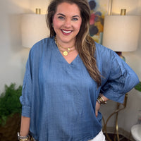 Woman wearing a denim v-neck dolman sleeve blouse