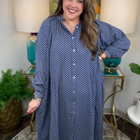Woman wearing a blue polka dot dress in a home setting with lamps and decor.