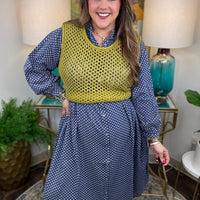 Woman wearing a blue polka dot dress with a yellow top in a home setting.