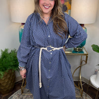 Woman wearing a blue polka dot dress in a home setting with lamps and decor.