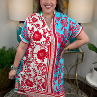 Woman wearing a colorful dress with floral patterns in a home setting
