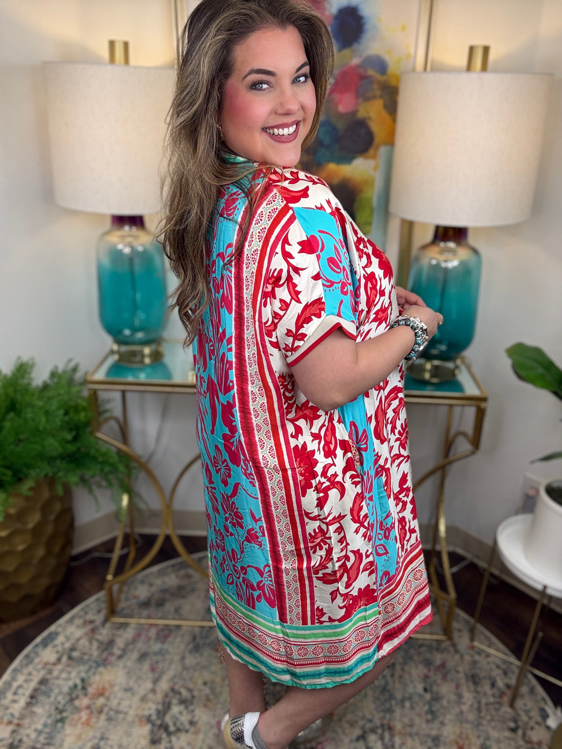 Woman wearing a colorful dress in a room with lamps and decor