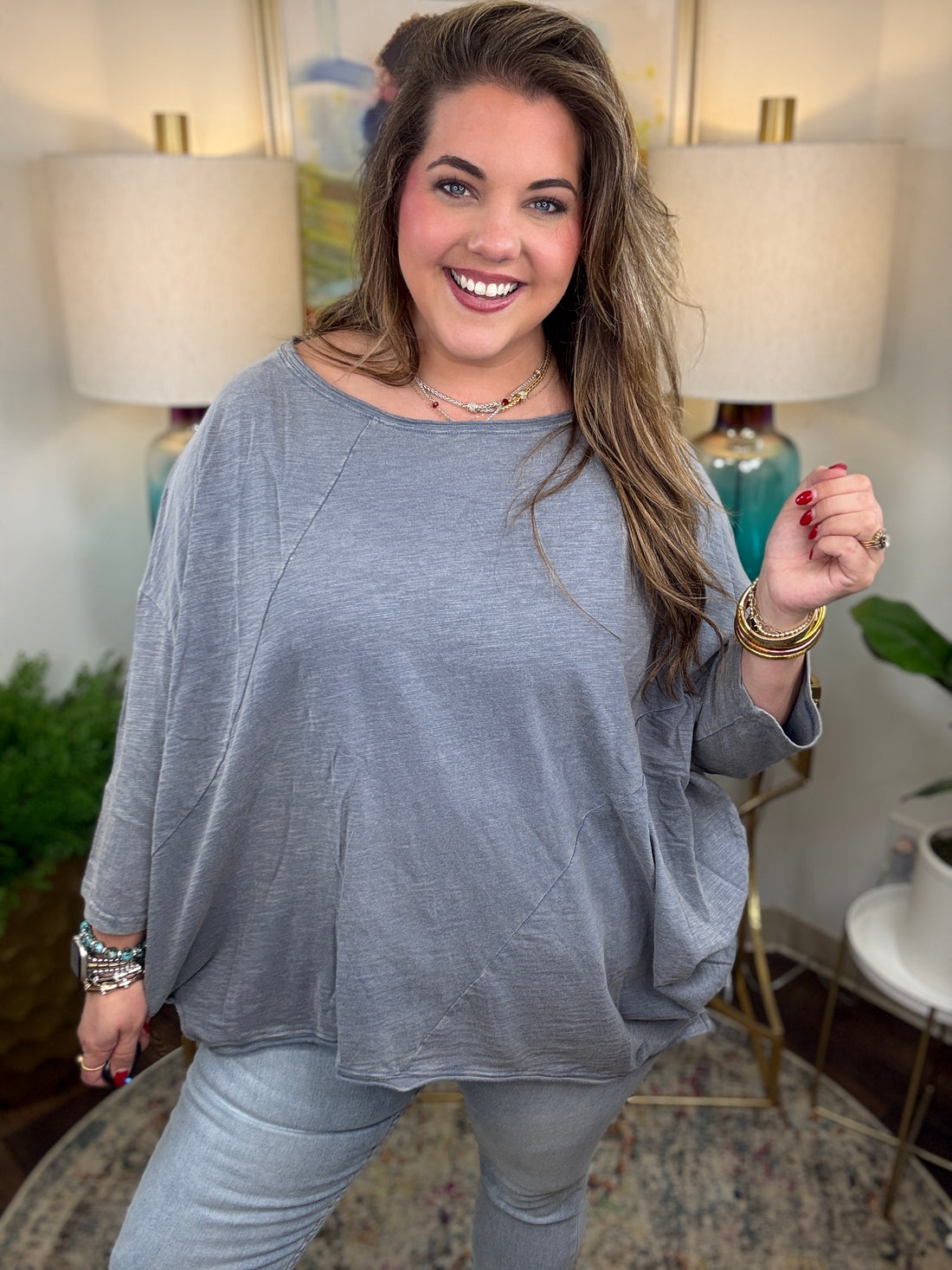 Woman wearing a gray oversized top and light blue jeans indoors.