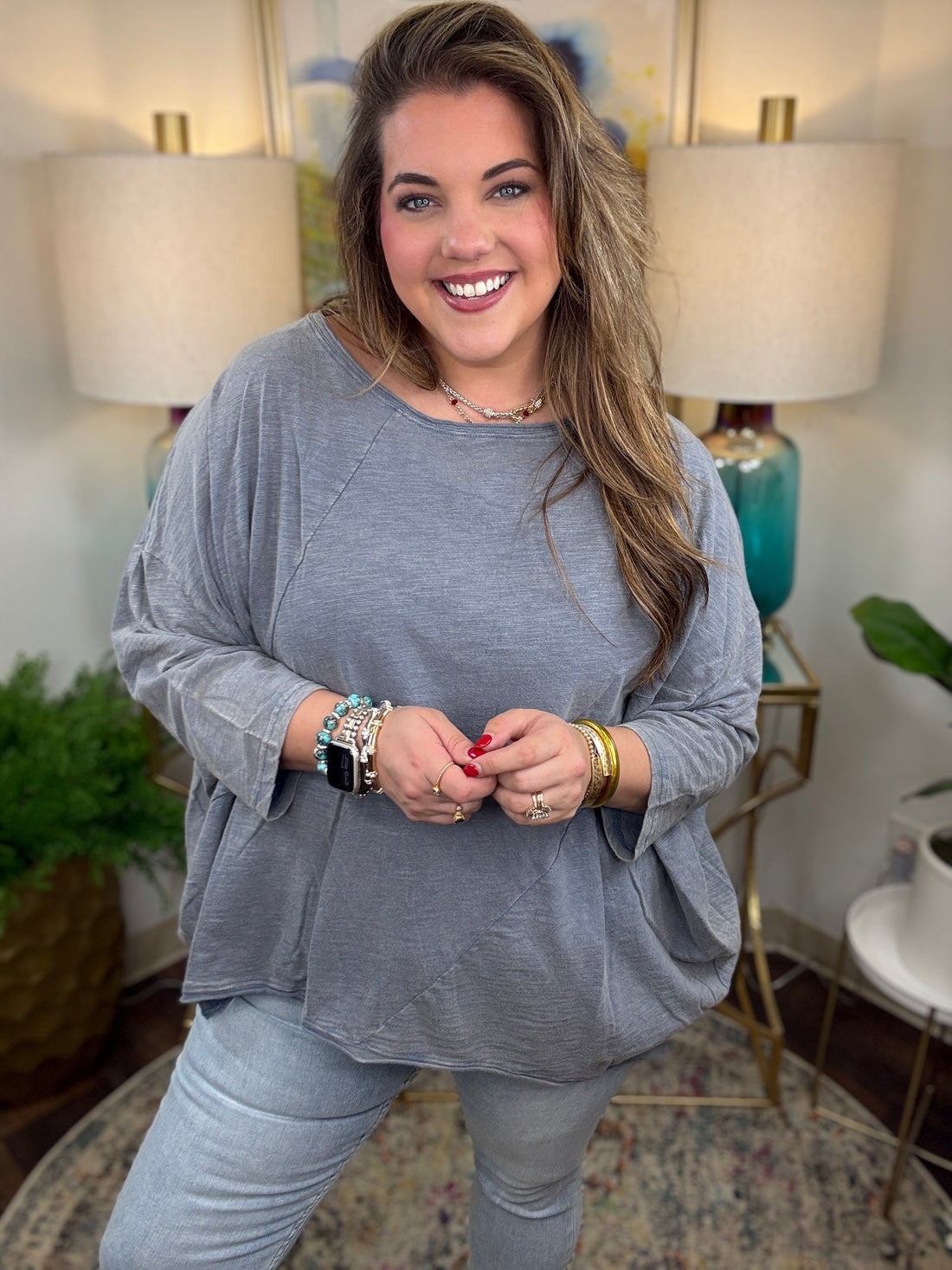 Woman wearing a gray oversized top and light blue jeans indoors.