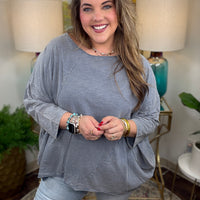Woman wearing a gray oversized top and light blue jeans indoors.