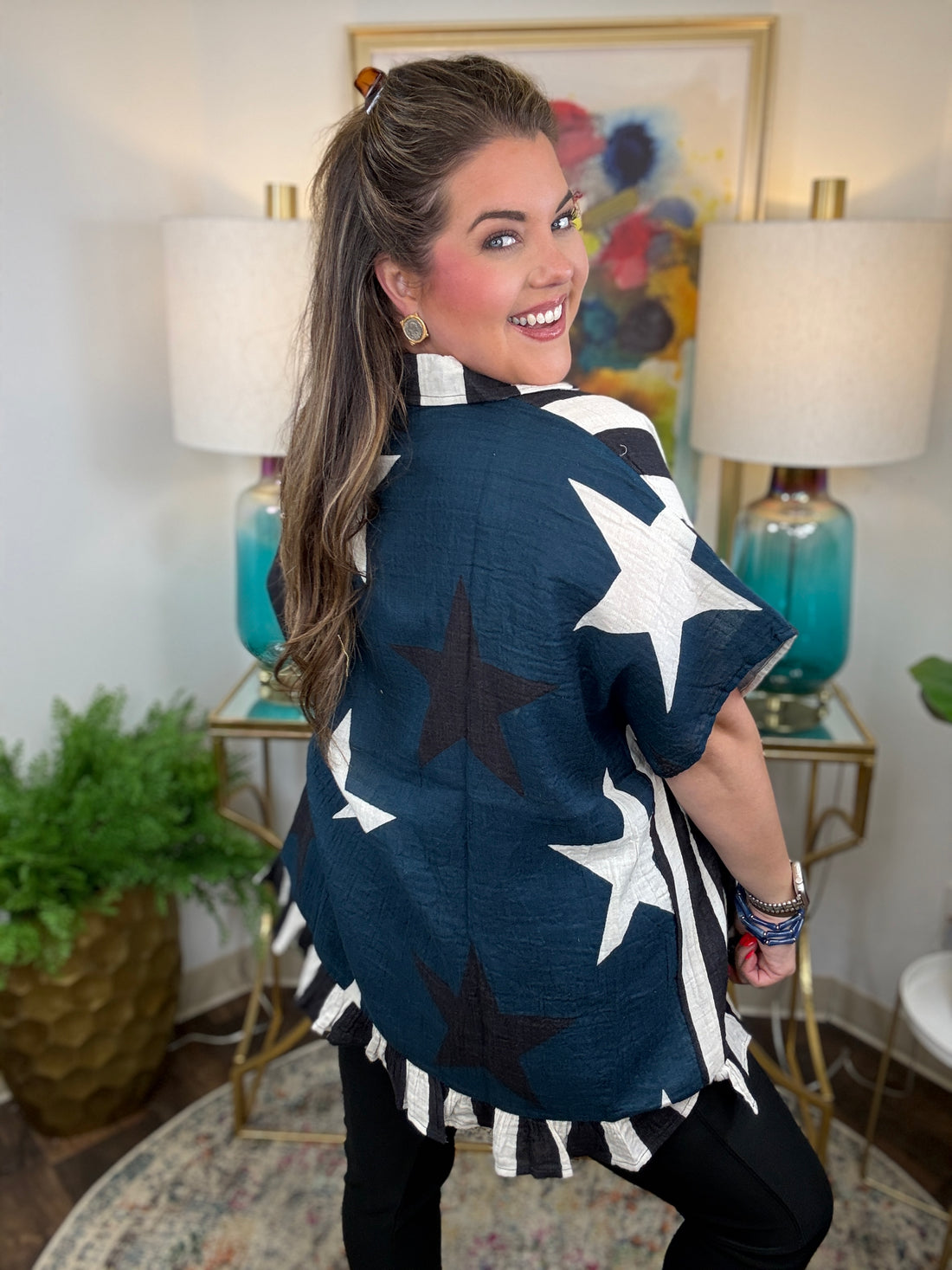 Woman wearing a cream and black striped oversized top with navy star back print a ruffle hem
