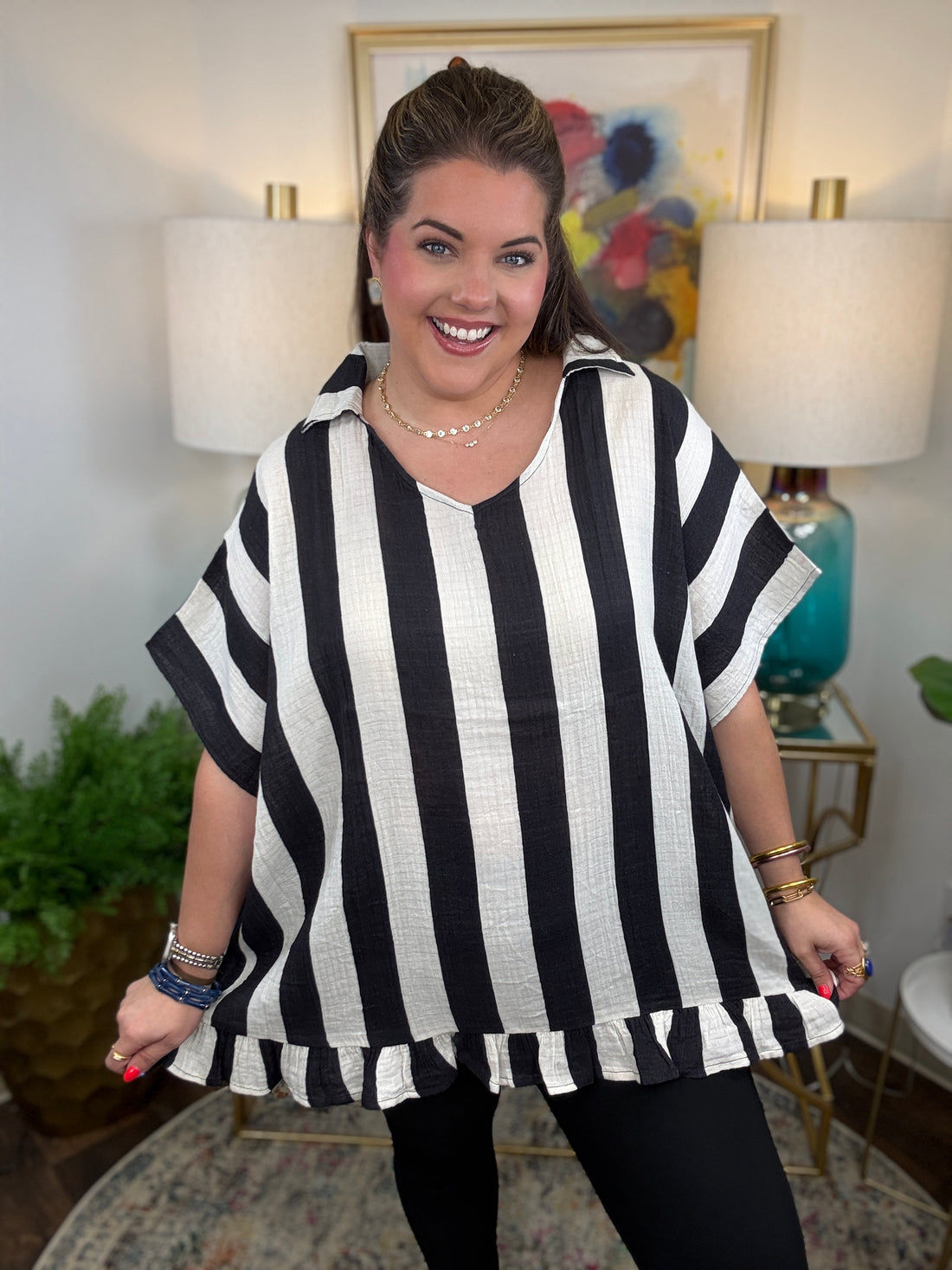 Woman wearing a cream and black striped oversized top with a ruffle hem
