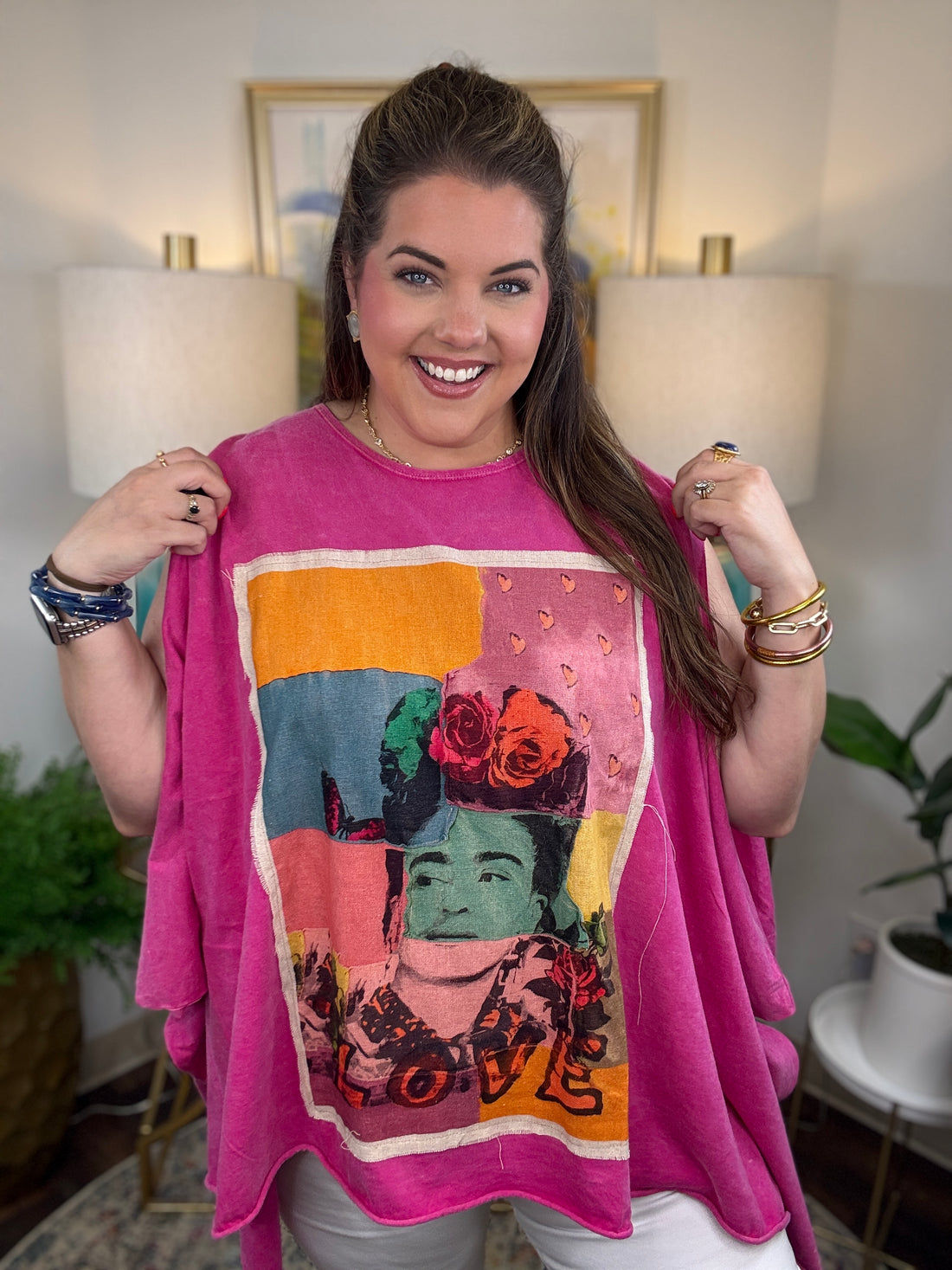woman wearing a sleeveless bright pink top with a large colorful Frida Kahlo graphic print on the front