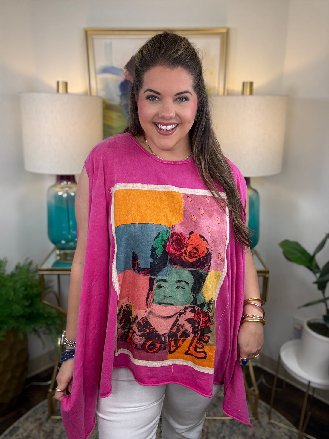 woman wearing a sleeveless bright pink top with a large colorful Frida Kahlo graphic print on the front