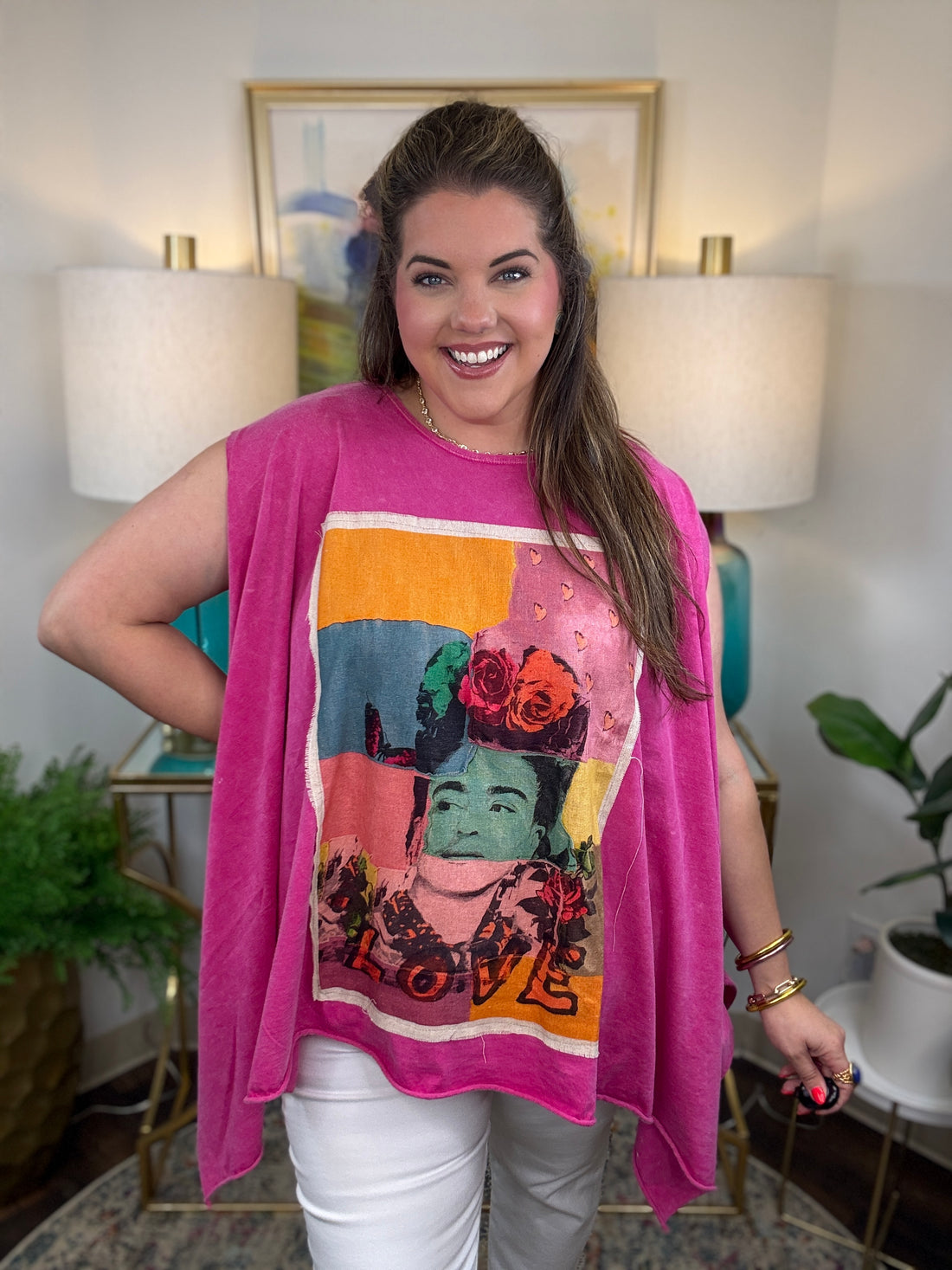 woman wearing a sleeveless bright pink top with a large colorful Frida Kahlo graphic print on the front