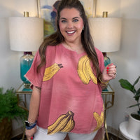 Woman wearing a pink short-sleeve top with a yellow banana print