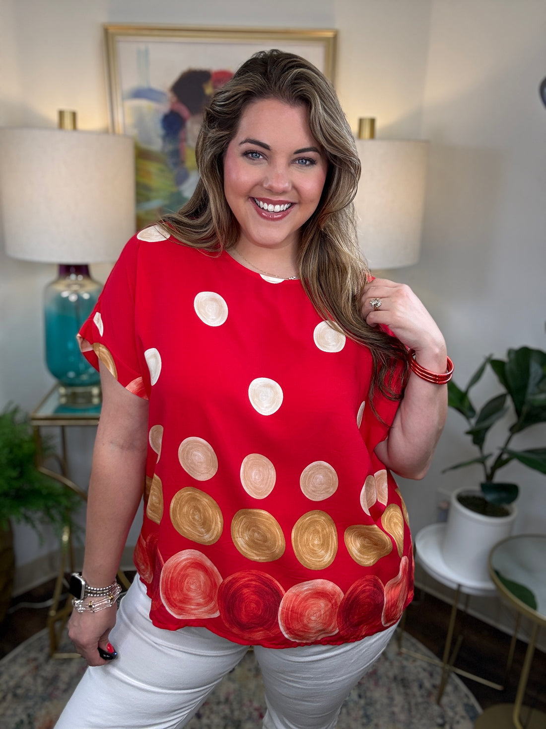 Woman modeling a red top with cream, tan, white and red polka dots on it
