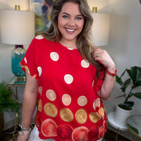 Woman modeling a red top with cream, tan, white and red polka dots on it